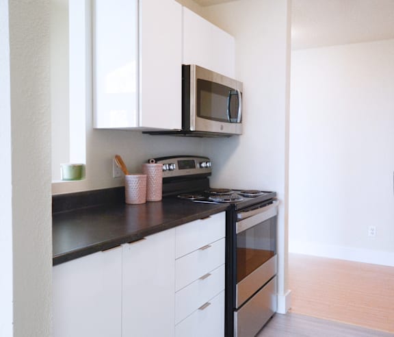 A modern kitchen with a stainless steel refrigerator and wooden flooring.