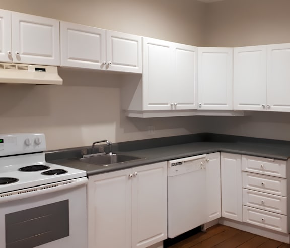 A modern kitchen with a stainless steel refrigerator and wooden flooring.