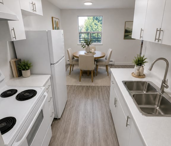 A modern kitchen with a stainless steel refrigerator and wooden flooring.