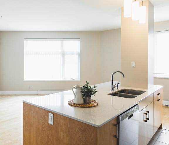 A modern kitchen with a stainless steel refrigerator and wooden flooring.