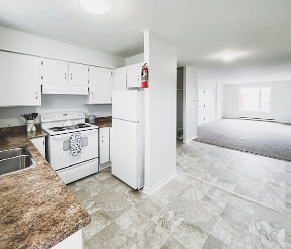 A modern kitchen with a stainless steel refrigerator and wooden flooring.