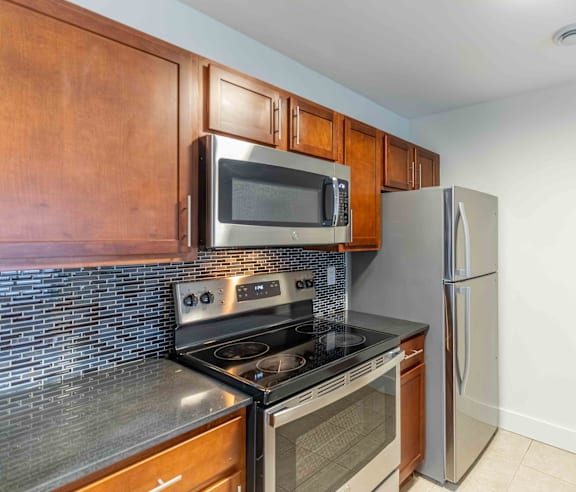 A modern kitchen with a stainless steel refrigerator and wooden flooring.