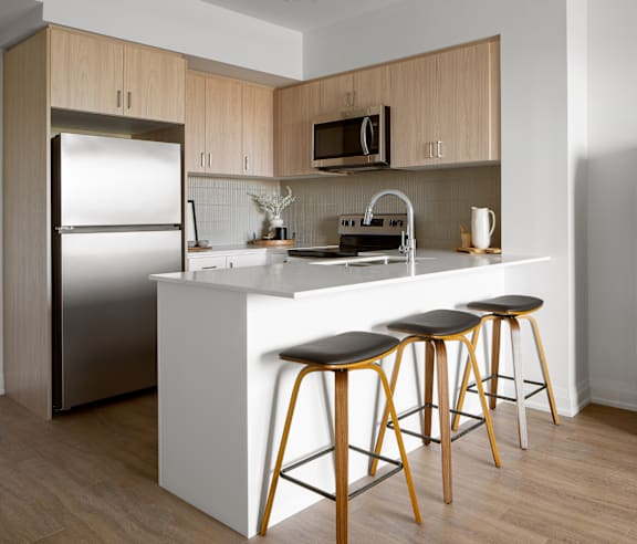 A modern kitchen with a stainless steel refrigerator and wooden flooring.