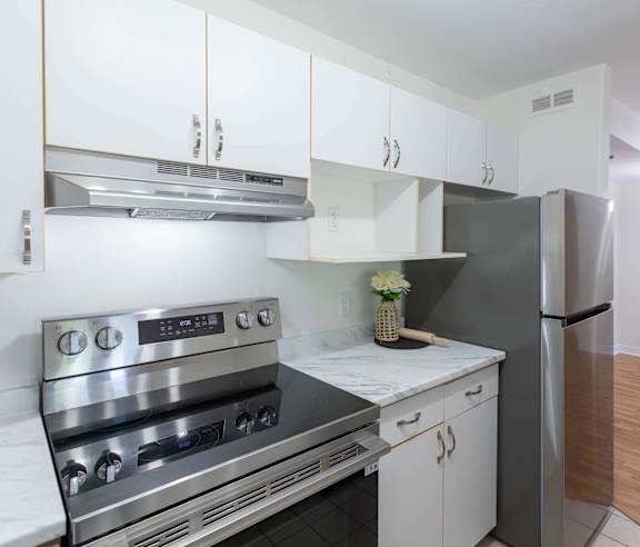 A modern kitchen with a stainless steel refrigerator and wooden flooring.