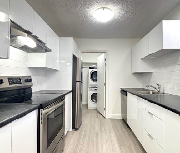 A modern kitchen with a stainless steel refrigerator and wooden flooring.