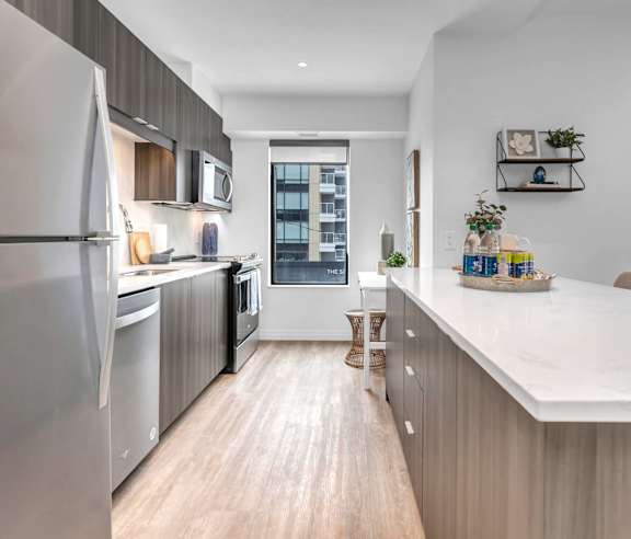 A modern kitchen with a stainless steel refrigerator and wooden flooring.