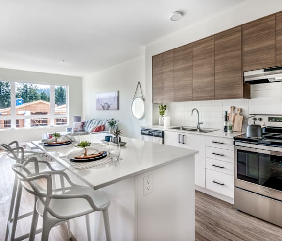 A modern kitchen with a stainless steel refrigerator and wooden flooring.
