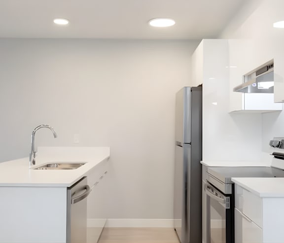 A modern kitchen with a stainless steel refrigerator and wooden flooring.