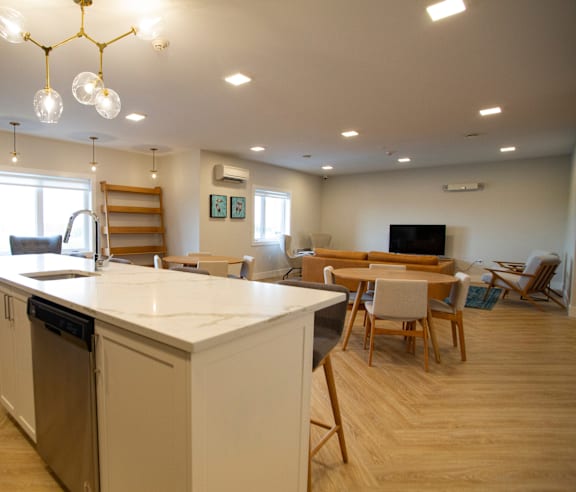 A modern kitchen with a stainless steel refrigerator and wooden flooring.