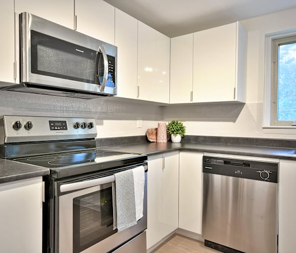 A modern kitchen with a stainless steel refrigerator and wooden flooring.