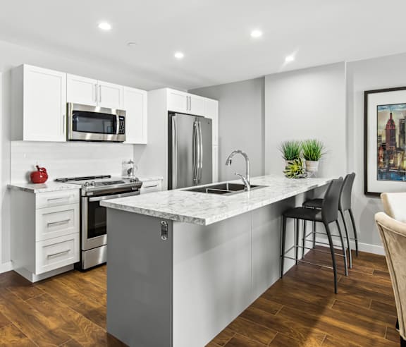 A modern kitchen with a stainless steel refrigerator and wooden flooring.