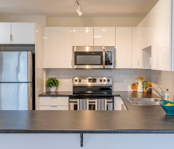A modern kitchen with a stainless steel refrigerator and wooden flooring.