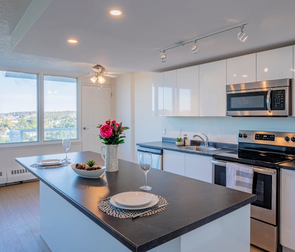 A modern kitchen with a stainless steel refrigerator and wooden flooring.