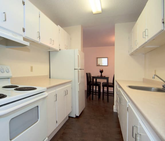 A modern kitchen with a stainless steel refrigerator and wooden flooring.