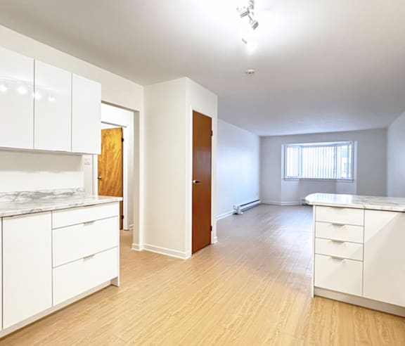 A modern kitchen with a stainless steel refrigerator and wooden flooring.