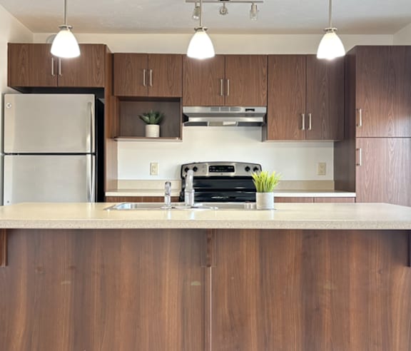 A modern kitchen with a stainless steel refrigerator and wooden flooring.