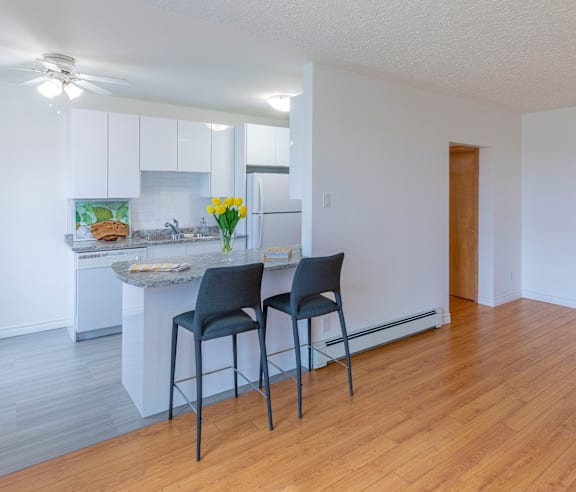 A modern kitchen with a stainless steel refrigerator and wooden flooring.