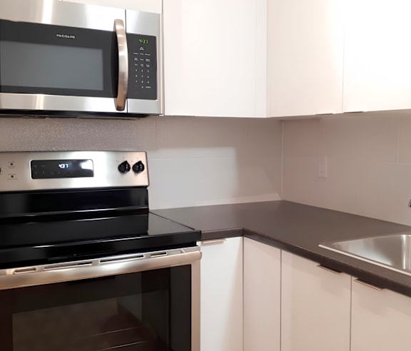 A modern kitchen with a stainless steel refrigerator and wooden flooring.