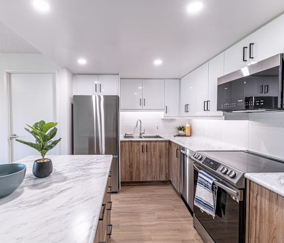 A modern kitchen with a stainless steel refrigerator and wooden flooring.