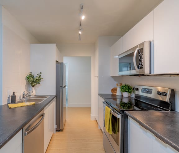 A modern kitchen with a stainless steel refrigerator and wooden flooring.
