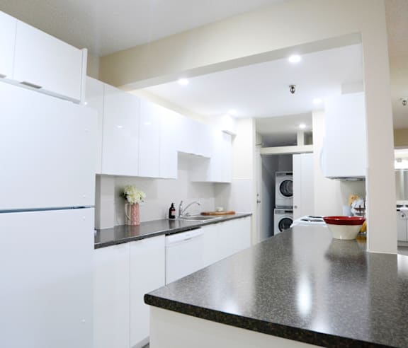 A modern kitchen with a stainless steel refrigerator and wooden flooring.
