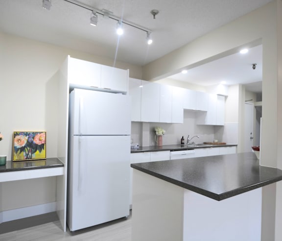 A modern kitchen with a stainless steel refrigerator and wooden flooring.