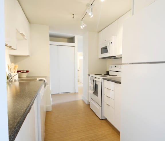 A modern kitchen with a stainless steel refrigerator and wooden flooring.