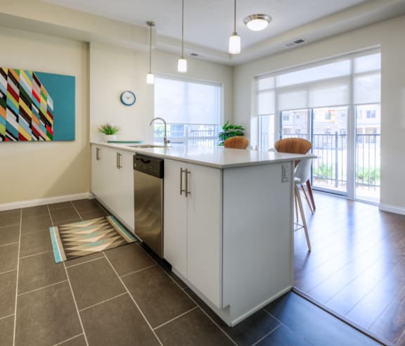 A modern kitchen with a stainless steel refrigerator and wooden flooring.
