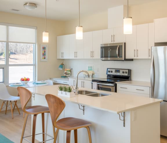 A modern kitchen with a stainless steel refrigerator and wooden flooring.