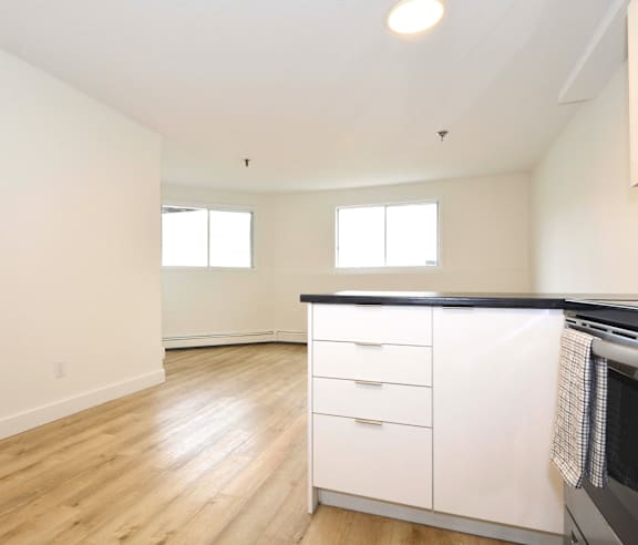 A modern kitchen with a stainless steel refrigerator and wooden flooring.