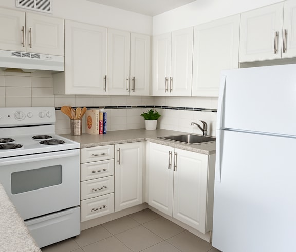 A modern kitchen with a stainless steel refrigerator and wooden flooring.