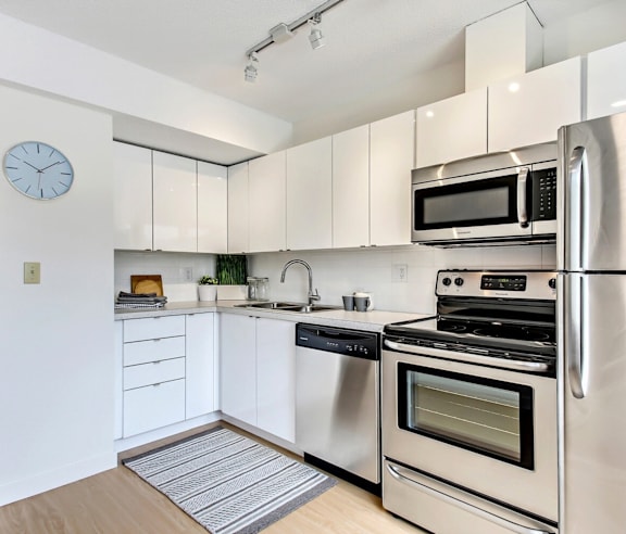 A modern kitchen with a stainless steel refrigerator and wooden flooring.