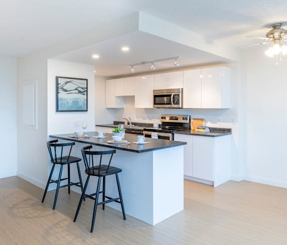 A modern kitchen with a stainless steel refrigerator and wooden flooring.