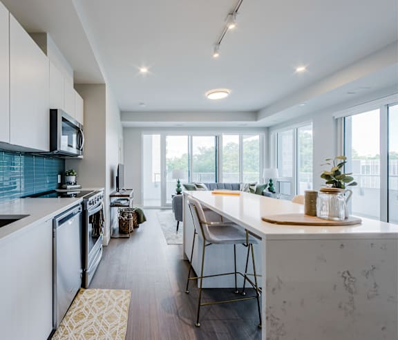 A modern kitchen with a stainless steel refrigerator and wooden flooring.