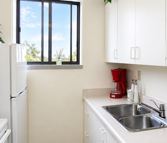 A modern kitchen with a stainless steel refrigerator and wooden flooring.