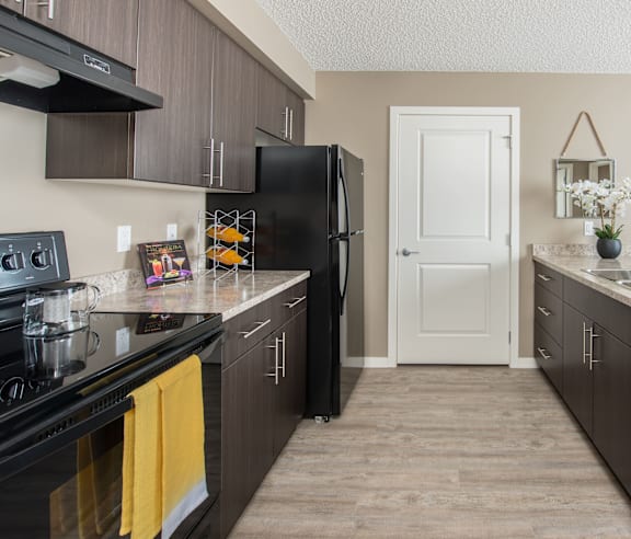 A modern kitchen with a stainless steel refrigerator and wooden flooring.