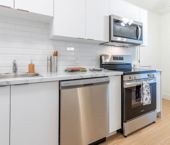 A modern kitchen with a stainless steel refrigerator and wooden flooring.