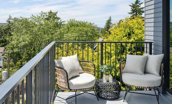 a balcony with two chairs and a table with two pillows on it