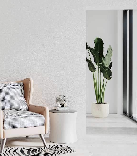 A chair with a pillow and a small table with a plant on it.