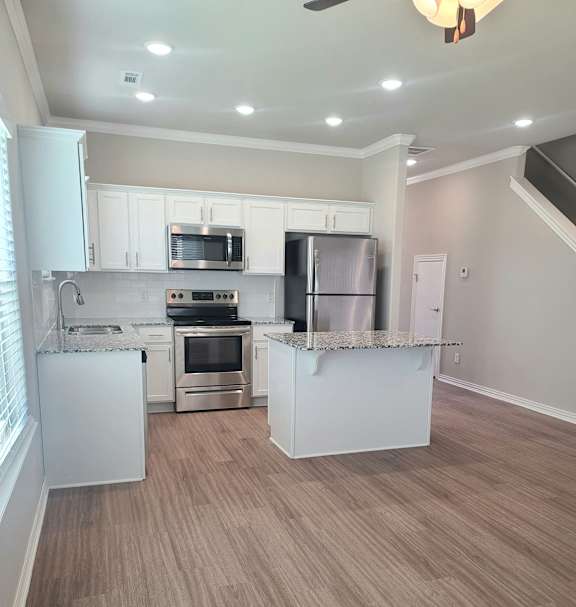 B4 Kitchen with laminate wood flooring, granite countertops, and stainless steel appliances
