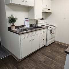 a kitchenette with a sink stove and dishwasher