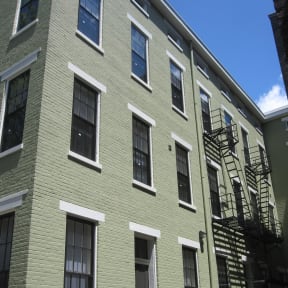the outside of a green building with a fire escape
