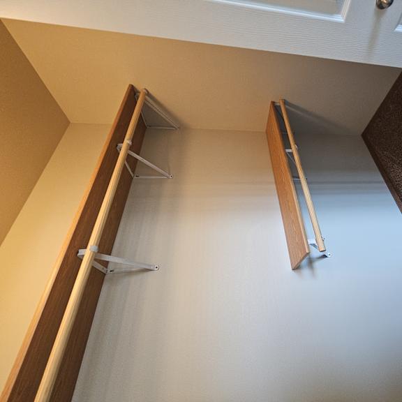 A white closet with a brown door and a white shelf.