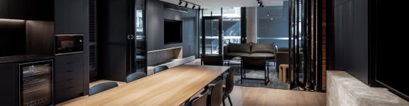 a dining area with a wooden table and chairs and a large tv on the wall