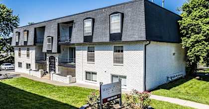 a white brick building with black shingles and a sign in front of it