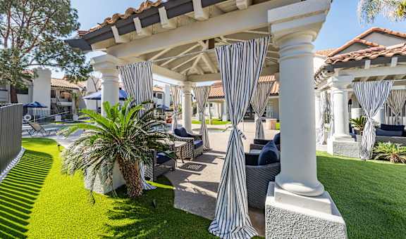 a patio with blue and white striped curtains and lawn furniture