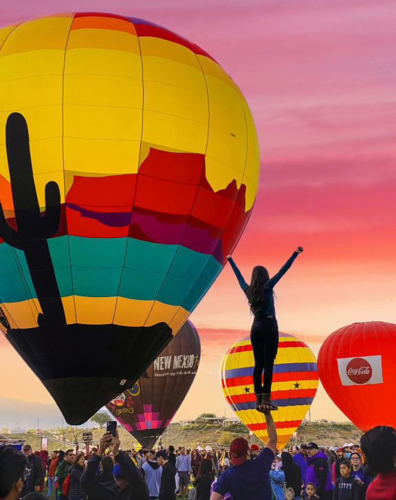 a woman is jumping up in a hot air balloon