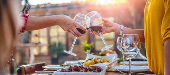 two people toasting wine glasses over a table of food at Viceroy Apartments, Durham , 27707