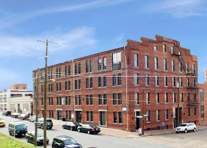 A red brick building with a parking lot in front.
