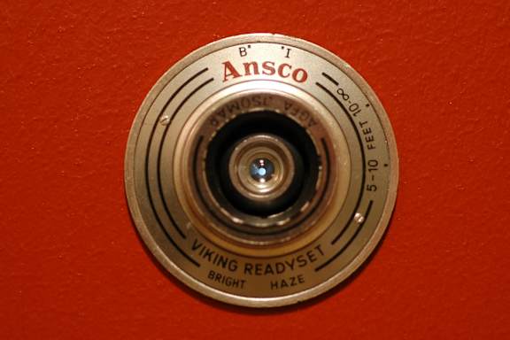 An Asco brand fire hydrant on a red wall.